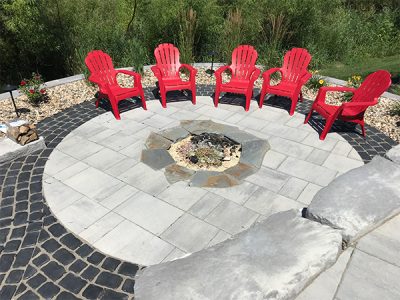 Chairs surround a fire pit installed by a residential landscaping company